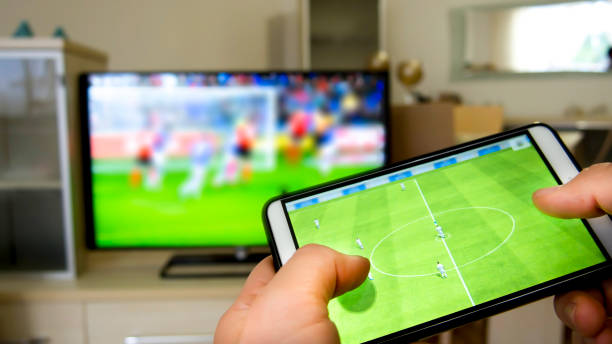 jugando al fútbol en un televisor con un smartphone - sport watching television broadcasting television fotografías e imágenes de stock