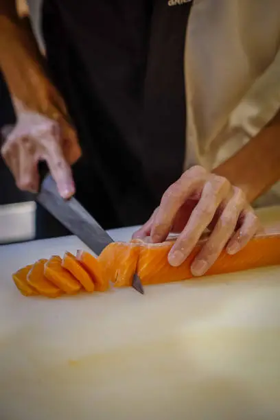 Chef use sharp knife slicing fresh salmon for sashimi