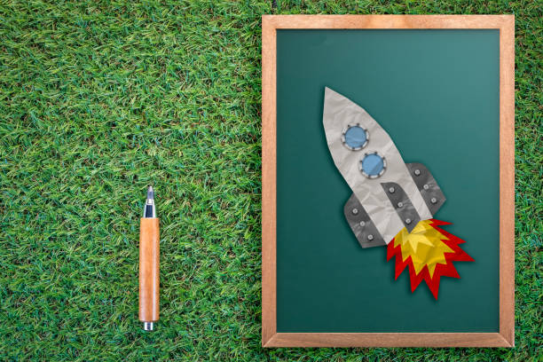 istock rocket paper icon on chalkboard  business startup ideas concept on green grass texture background 939356098