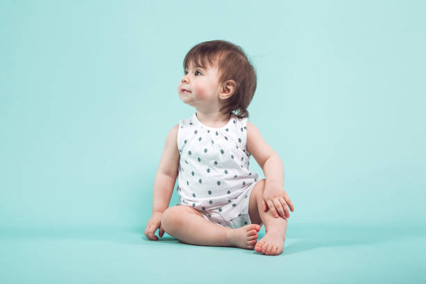 istock Cute small girl crawling sitting in studio on blue background 939356366