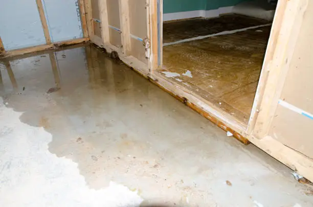 View of a concrete basement floor full of water caused by sewer backflow due to clogged sanitary drain