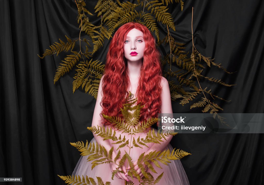 Beautiful pre-raphaelite girl with curly red hair with a flying tulle dress on black background One Woman Only Stock Photo