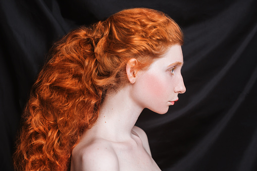 Woman With Long Curly Red Hair Gathered In Ponytail On Black Background  Redhaired Girl With Pale Skin Blue Eyes Unusual Appearance Without Makeup  Natural Beauty Girl From The Era Of Renaissance Stock