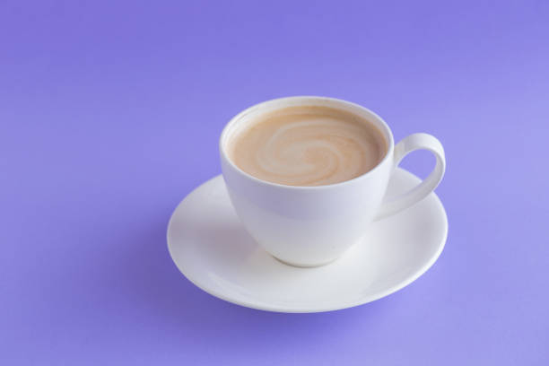 istock white a cup of coffee on violet background toned. 939385244