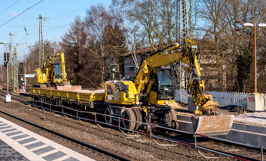 Schwerte, Germany - February 5, 2018: Railway construction machinery. Construction of the railway platform. The excavator is mounted on wagon wheels. Carriage with gravel.