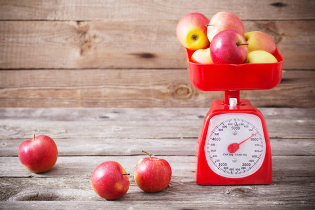 jabłka na czerwonej skalach - weight scale apple comparison balance zdjęcia i obrazy z banku zdjęć