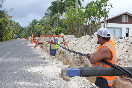 Te Aponga Uira workers lay high voltage underground cable installation in Rarotonga. Te Aponga Uira (TAU) power utility provides 90% of the Cook Islands electricity demand.