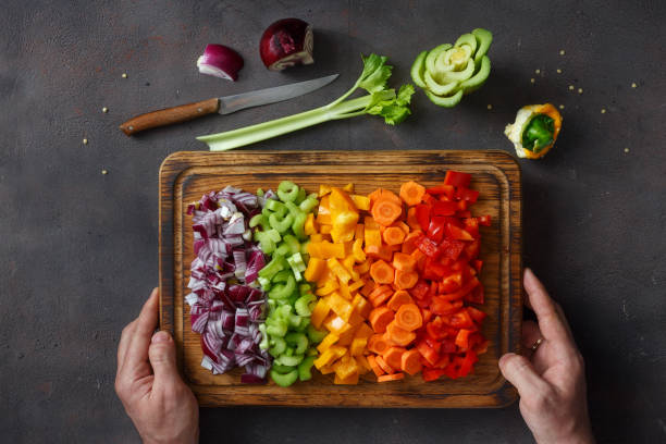 Male hands holding cutting board with sliced fresh vegetables