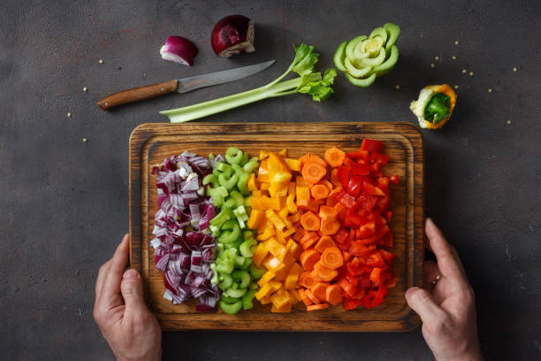мужские руки, держащие разделочных доску с нарезанными свежими овощами - vegetable cutter стоковые фото и изображения