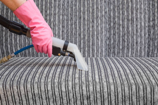 istock Dry cleaner's employee hand cleaning a modern sofa with professionally extraction method. Textile upholstered furniture. Early spring regular cleanup. Commercial cleaning company. Service concept. 939444130