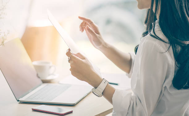 istock Cropped image of businesswoman holding document paper while working at office 939447528