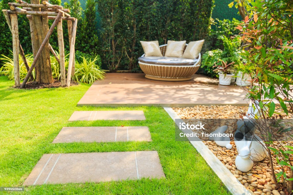 Stone pathway on lawn in the garden. Stone pathway on lawn in the garden with sofa and nature background. Yard - Grounds Stock Photo
