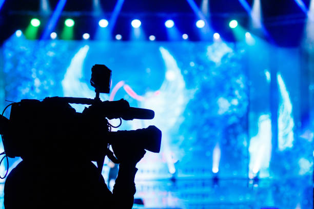 operador de câmera de vídeo profissional trabalhando com seu equipamento, fundo azul - entrevista evento - fotografias e filmes do acervo
