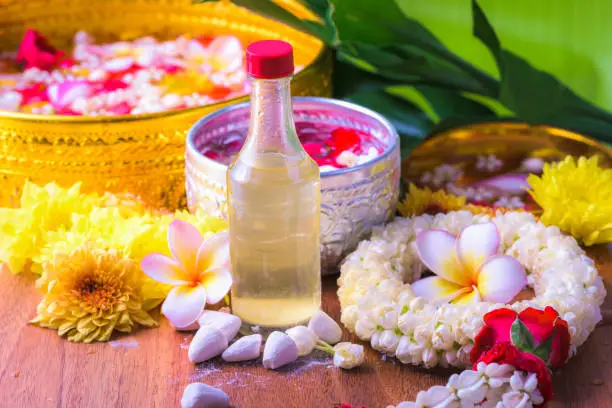 Photo of Thai traditional jasmine garland and Colorful flower in water bowls decorating and scented water, perfume, marly limestone for Songkran Festival or Thai New Year.