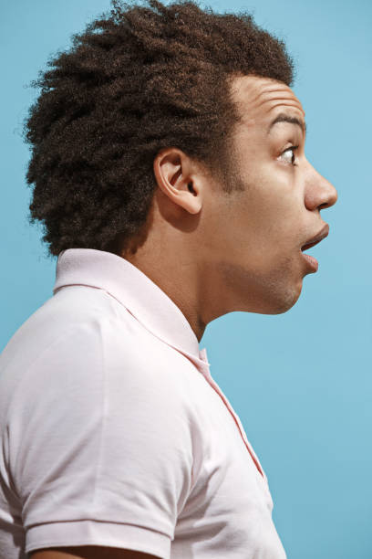 istock The young attractive man looking suprised isolated on blue 939471686