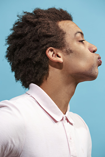 I kiss you. Portrait of attractive afro man with kiss on lips. blue studio. Beautiful male portrait. Young happy emotional funny man looking away. Human facial emotions concept. Trendy colors. Profile