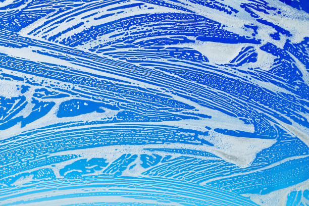 istock Window cleaning. Glass in soap foam against blue sky background 939479976