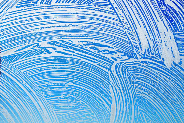 istock Window cleaning. Glass in soap foam against blue sky background 939479978