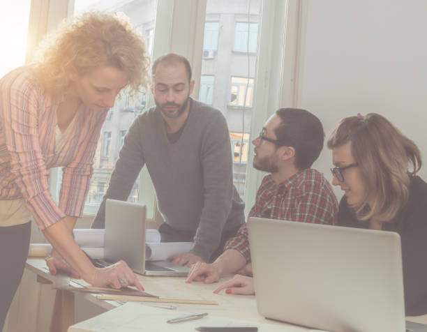 istock Group of young architects in the sunny office. 939480012