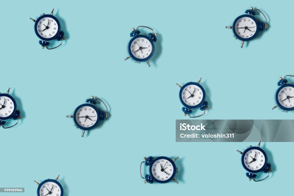 Flat lay retro beautiful new alarm clock on blue color background. Pattern. Top Flat lay retro beautiful new alarm clock on blue color background. Pattern. Top view Time Stock Photo