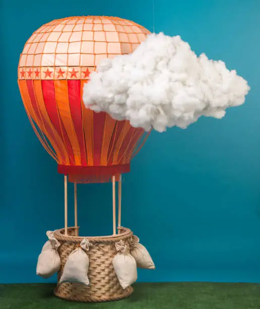 The model of hot air balloon with wicker basket for childrens game. The props of photo studio. Studio shooting on blue background
