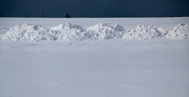 istock snow field. The plain is covered with white snow under a blue sky with thick white clouds. before a snowfall, a storm, a snowstorm. premonition of a blizzard. in anticipation of a blizzard. 939494030