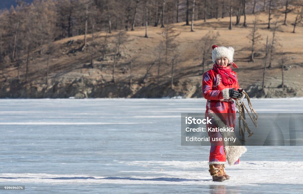 mongolian woman on a frozen lake Hatgal, Mongolia, 1st March 2018: mongolian woman in a beautiful red deel on a frozen lake Khovsgol Adult Stock Photo