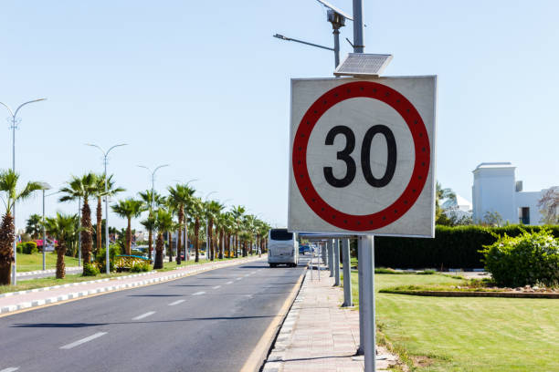 znak ograniczenia prędkości z panelem słonecznym na drodze z palmą w letni dzień. ograniczenie prędkości wynosi 30 km/h na szutrowej drodze - kilometers per hour zdjęcia i obrazy z banku zdjęć