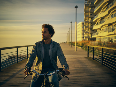 Shot of a young man going for a bicycle ride along the promenade