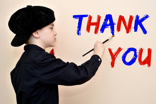 Young painter with the brush writing THANK YOU on the wall