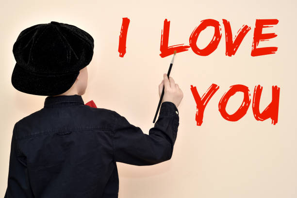 istock Young painter with the brush writing I LOVE YOU on the wall 939501584