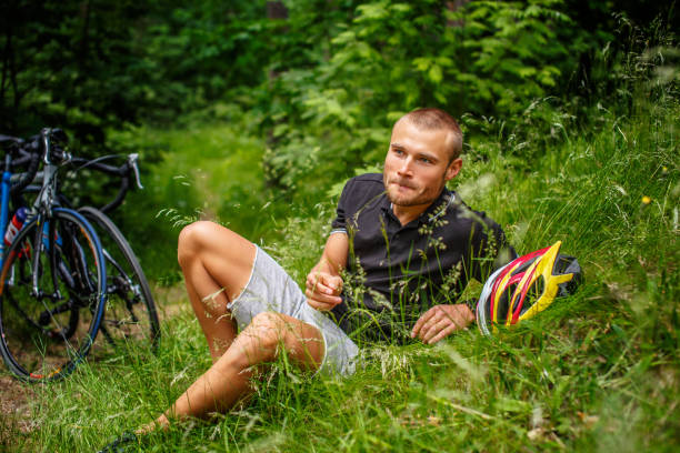 Positive male resting on a grass after bicycle ride.