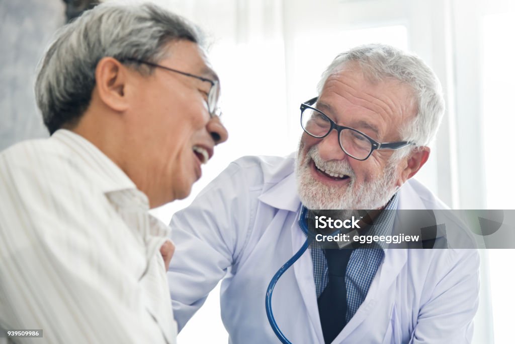 Happiness of Senior male Doctor with Asian male patient. Happiness People.  Senior male Doctor and Asian male patient are talking in the medical room together. Smiling. Doctor Stock Photo