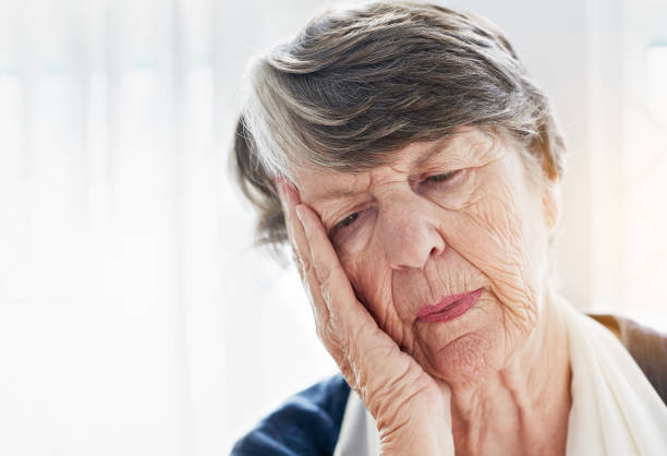 istock Old woman resting her face on her hand looks sad 939514120