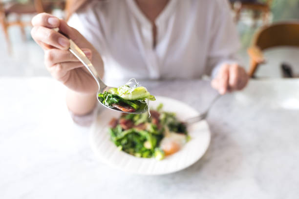 istock A woman scooping warm salad with spoon before eating on table in the restaurant 939518284