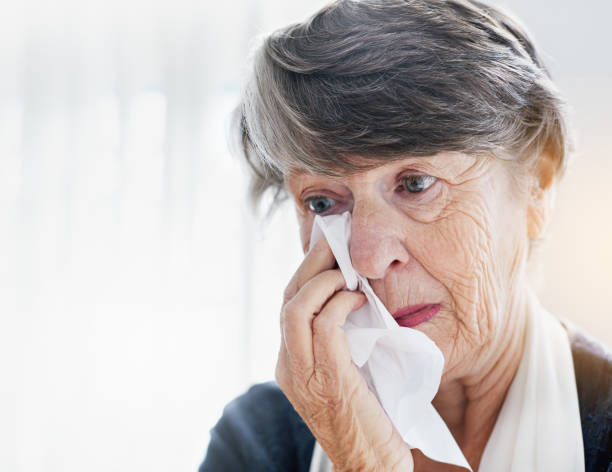 Sad senior woman wiping eyes with tissue An unhappy senior woman wipes her eyes with a facial tissue, grimacing. facial tissue photos stock pictures, royalty-free photos & images