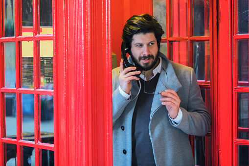 Portrait Of Businessman Talking At Telephone Booth, London