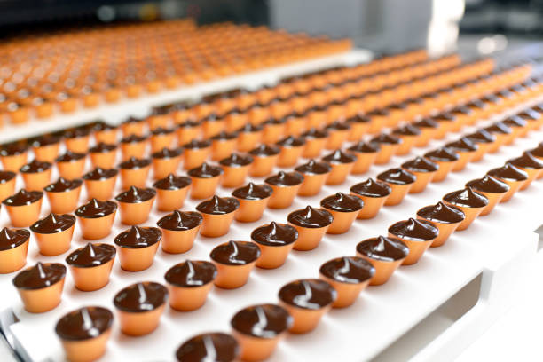 production de pralines dans une usine pour l’industrie alimentaire - convoyeur automatique avec du chocolat - cookie baked sweet food food photos et images de collection