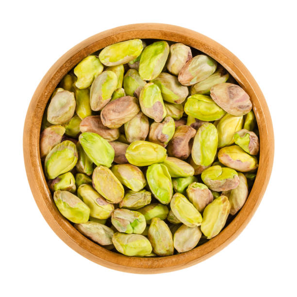 istock Shelled roasted pistachio kernels in wooden bowl over white 939538096