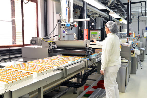 production de pralines dans une usine pour l’industrie alimentaire - travailleur de ceinture de convoyeur avec du chocolat - usine agro alimentaire photos et images de collection