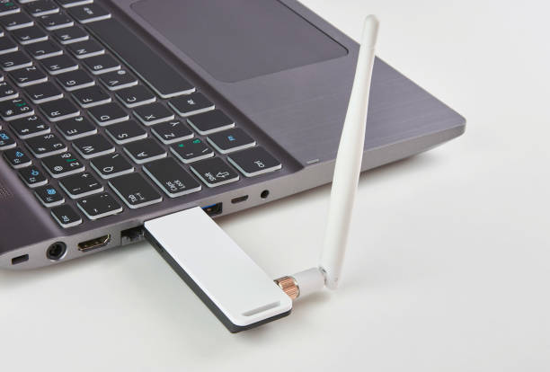 Silver laptop with USB modem plugged in with an antenna, on a white board table Silver laptop with USB modem plugged in with an antenna, on a white board table plug adapter stock pictures, royalty-free photos & images