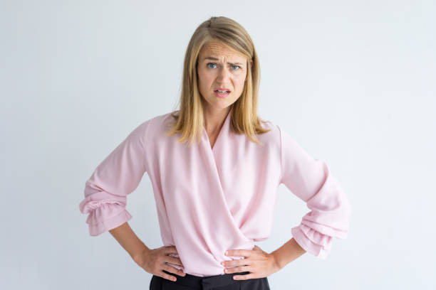 Portrait of displeased young businesswoman Portrait of young Caucasian businesswoman wearing pink blouse standing with hands on waist displeased at some rude behavior. Irritation, misunderstanding concept disgust stock pictures, royalty-free photos & images