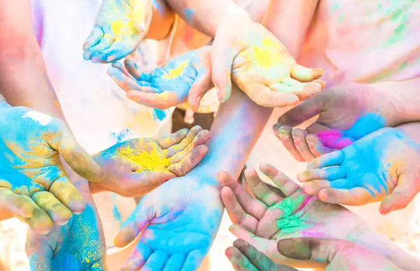 Photo of Bunch of colorful hands of friends group having fun at beach party on holi color festival summer vacation - Young people enjoying time together - Youth friendship concept with multicolored powder game