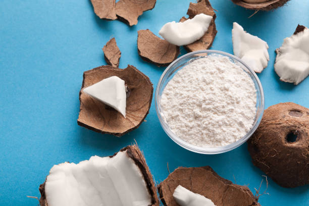 Plate with coconut flour and nuts on blue background