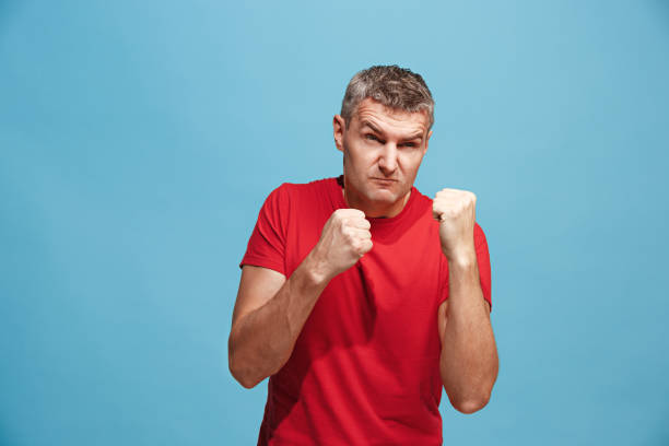 istock The young emotional angry man screaming on blue studio background 939566926
