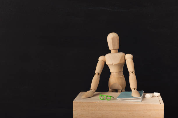 istock Wooden figure at workplace against black background 939567144
