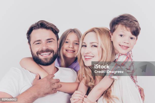 Family Photo Portrait Four Relatives Are Hugging On The White Background Smiling At Home Blond Mum Is Piggy Backing The Cute Small Son Stock Photo - Download Image Now