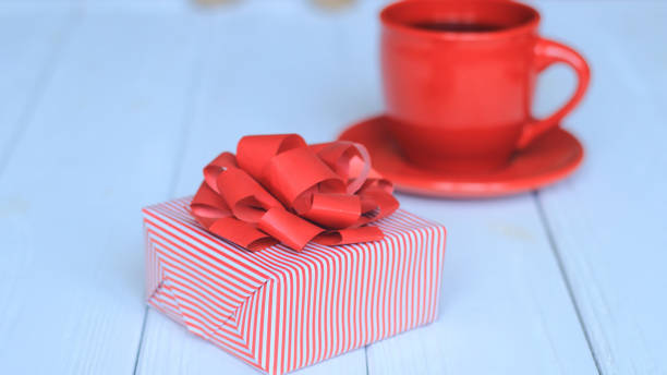 istock close-up background image of red Cup and gift box on light background. 939568038