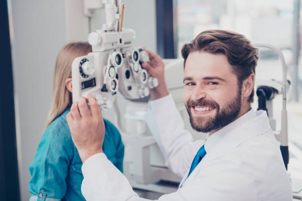 nahaufnahme von attraktiven fröhlich brunet bärtigen optiker, auge anblick check up für kleine blonde mädchen in seinem büro zu tun lächelnd - serving people teenage girls female stock-fotos und bilder