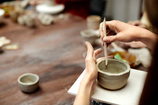 istock Woman molding clay with tool at table 939571770